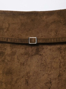 Detailed close-up of brown suede skirt waist with slim belt and silver square buckle