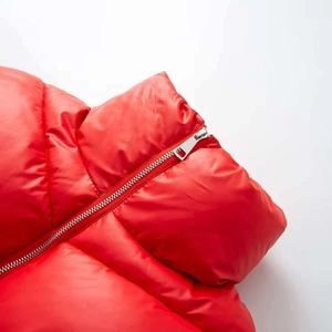 Detailed macro view of shiny red quilted puffer jacket with silver metallic zipper