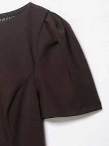 Detailed view of dark brown dress fabric with puff sleeve stitching and brand label