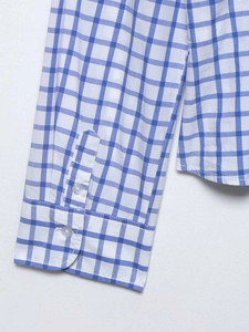 Détail du poignet d'une chemise à carreaux bleu et blanc avec deux boutons et couture