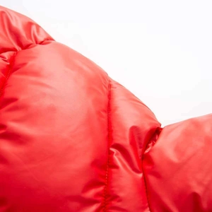 Macro shot of bright red quilted nylon fabric showing soft padding and premium texture