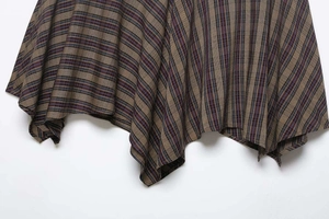 Detail view of plaid skirt with asymmetrical hem and classic multi-color check pattern