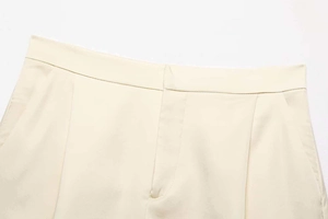 Detail of beige satin shorts waistband with lace trim, hidden pockets and zipper