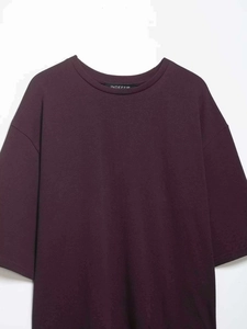 Detail of round neckline and brand label on a dark purple cotton knit short sleeve tee