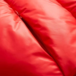 Detail of red quilted winter jacket featuring smooth shiny fabric and matching zipper