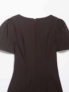 Detail of round neckline and back invisible zipper on dark pleated mini dress