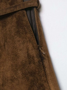 Detailed close-up of dark brown suede fabric texture with concealed side zipper and belt loop
