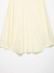 Close-up of curved hem and buttoned cuffs on light beige poplin long sleeve shirt