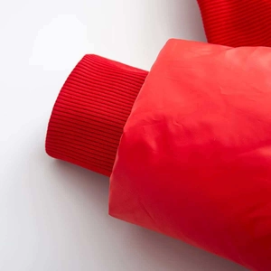 Close-up of red winter coat ribbed cuff with tight knitting and precise stitching detail