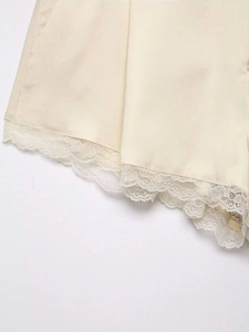 Detail of satin fabric texture with exquisite white lace trim on cream shorts