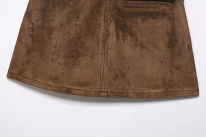 Detail view of brown suede mini skirt showing fine stitching and straight pocket line