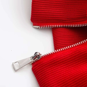 Macro shot of red ribbed knit sweater with silver metal zipper detail and texture