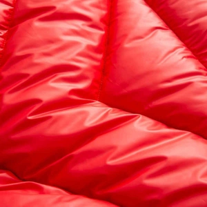 Close-up of bright red quilted water-resistant fabric with glossy metallic finish