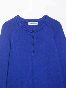 Détail d'un pull en maille bleu roi avec col rond côtelé et quatre boutons foncés
