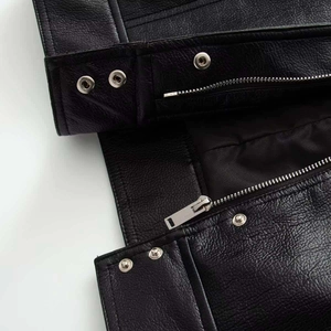 Close-up of black faux leather bomber jacket featuring silver metal zippers and buttons