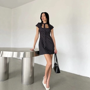 Mini-robe vintage noire à pois avec lien au cou et découpe présentée sur mannequin