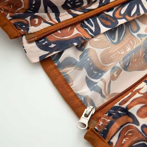 Detailed macro view of triple metal zippers on vintage floral print hooded jacket