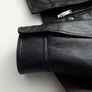 Close-up of black faux leather bomber jacket showing silver zipper and grain texture