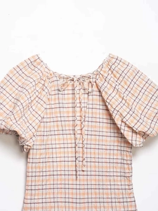 Détail d'une chemise à carreaux vintage avec manches bouffantes et nœud décoratif au col