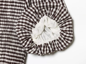 Détail d'un haut vichy smocké montrant la texture des manches bouffantes et la doublure