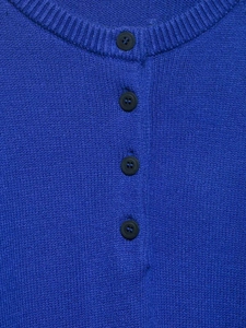 Détail du haut en tricot bleu roi avec col rond et quatre boutons noirs sur la patte