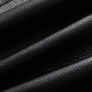 Close-up detail of premium black faux leather texture with natural grain finish on jacket