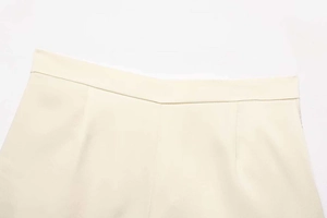 Close-up of beige satin textured shorts waist with refined stitching and woven fabric detail