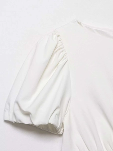Close-up detail of pleated puff sleeve and textured fabric on a white summer dress