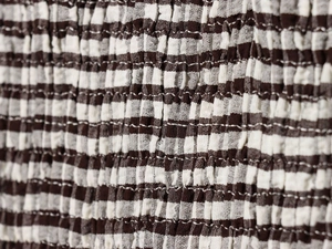 Détail du tissu smocké à carreaux marron et blanc avec finition élastique texturée
