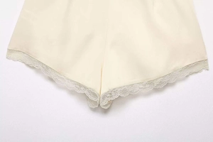 Detail showing cream satin texture and delicate eyelash lace trim on summer shorts
