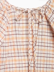 Gros plan sur la texture du tissu à carreaux orange avec un nœud élégant au col
