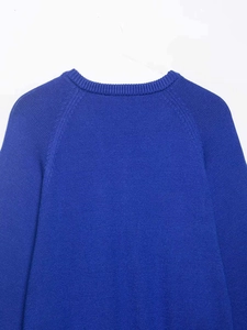 Détail d'un pull en maille bleu roi montrant les manches raglan et les coutures du col