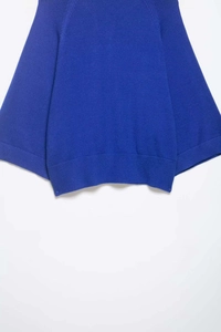 Détail d'un haut en tricot bleu montrant l'ourlet côtelé et la texture de maille