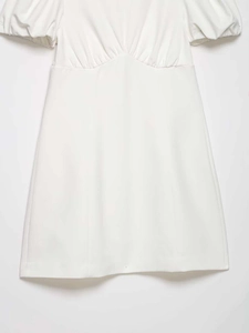 Detail of white mini dress featuring pleated V-neckline and puff short sleeves texture