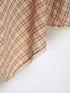 Vue macro détaillée du tissu à carreaux avec une bordure en dentelle marron et rose