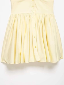Detail of the light yellow dress showing fine pleated waist and matching button closures