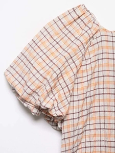 Détail de manches bouffantes à carreaux orange avec poignets élastiques froncés sur haut