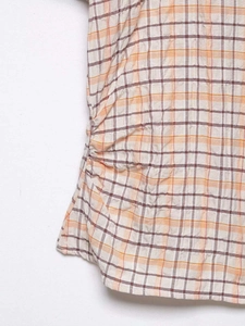 Détail de la blouse à carreaux avec cordon de serrage et plis sur le côté du vêtement