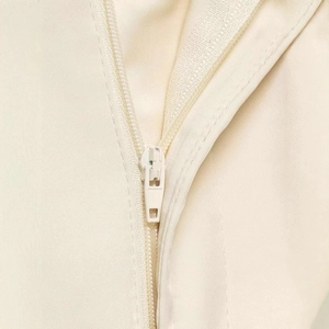 Close-up of seamless zipper and high-quality fabric texture on beige satin shorts