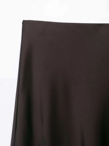 Détail de la jupe midi en satin marron avec une texture lisse et un aspect brillant