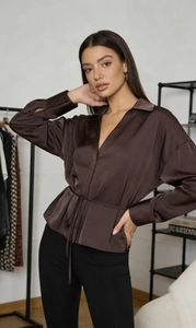 Detail eines schokobraunen Satin-Langarmshirts mit Bindegürtel und seidiger Textur