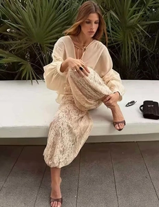 Outdoor shot of a beige puff sleeve top and lace maxi skirt in a summer vacation style
