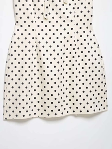 Detailaufnahme des weißen Polka-Dot-Kleides mit Neckholder-Design und Schleife