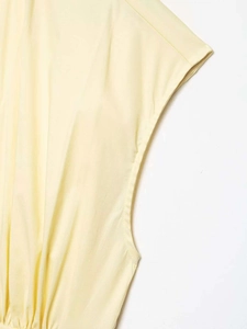 Detail of pale yellow sleeveless dress showing precise armhole binding and waist pleat details