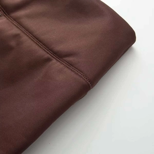 Detailed macro view of dark brown yoga pants showing professional flatlock stitching