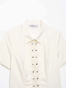 Detail of white short sleeve shirt with ruffled front and decorative metal buttons