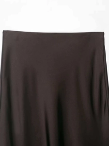 Gros plan détaillé de la taille et de la texture satinée lisse de la jupe midi marron