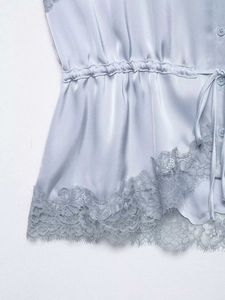 Close-up of light blue satin camisole with delicate eyelash lace hem and side drawstring