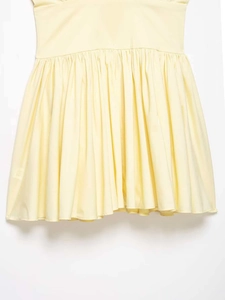 Detail of light yellow gathered waist and pleated fabric texture on a summer dress