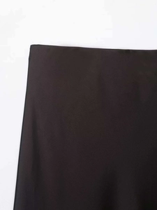 Détail de la jupe en satin noir montrant la texture soyeuse et la finition brillante